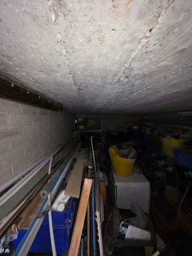Garage interior packed with shelving, boxes and stored equipment before clearance, typical of jobs we clear in Broadstone